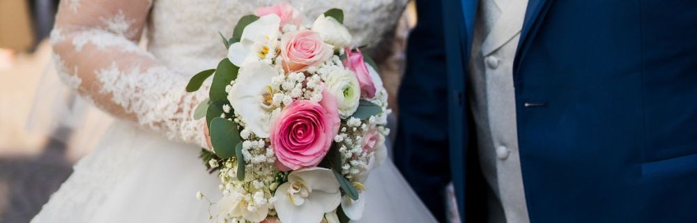 Brautpaar mit einem Brautstrauß aus weißen und rosafarbenen Blumen.