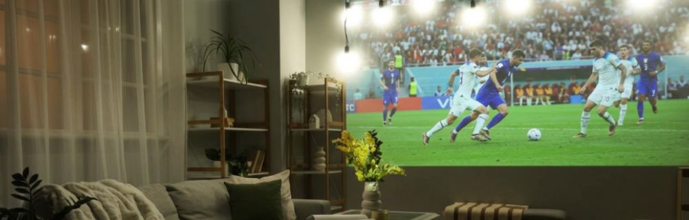 Wohnzimmer mit Großbildprojektion eines Fußballspiels an der Wand.