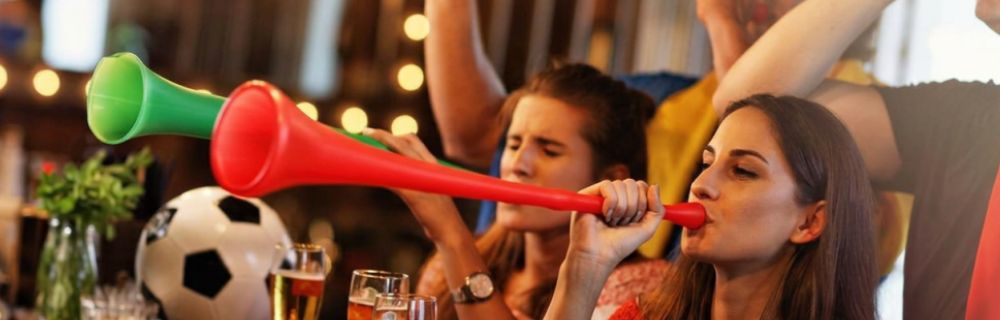 Fußballfans feuern ihr Team mit Tröten und Jubel an.