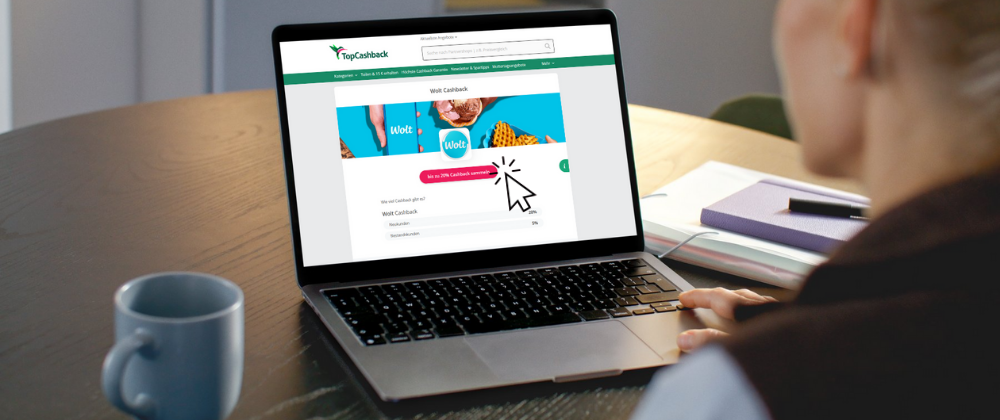 Person an Laptop mit Website von TopCashback auf dem Bildschirm.