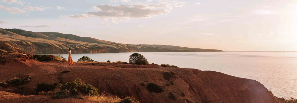 Küstenlandschaft bei Sonnenuntergang mit Klippen und Meer.