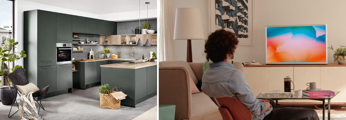 Moderne Küche mit Küchenflächen und daneben Wohnzimmer mit Person vor einem Fernseher.