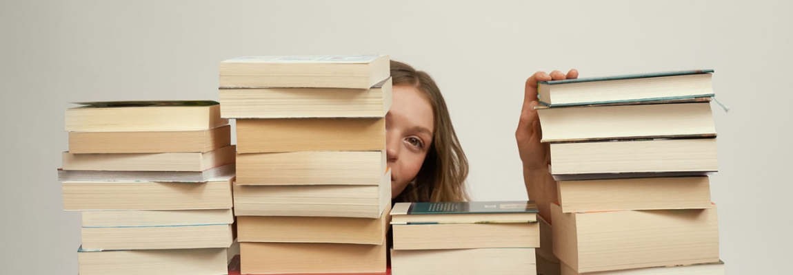 Junge Frau hinter Bücherstapeln.